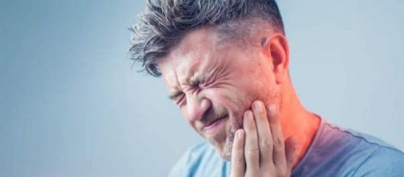 A man holding his jaw in pain.