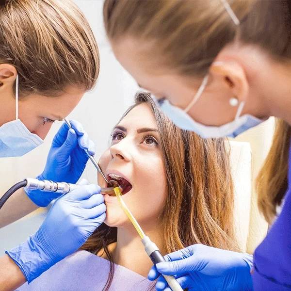 Dental professionals examine and work on patient teeth in a professional clinical setting