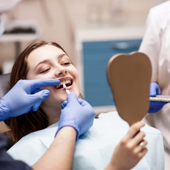 Patient checking her smile in a hand mirror after cosmetic treatment